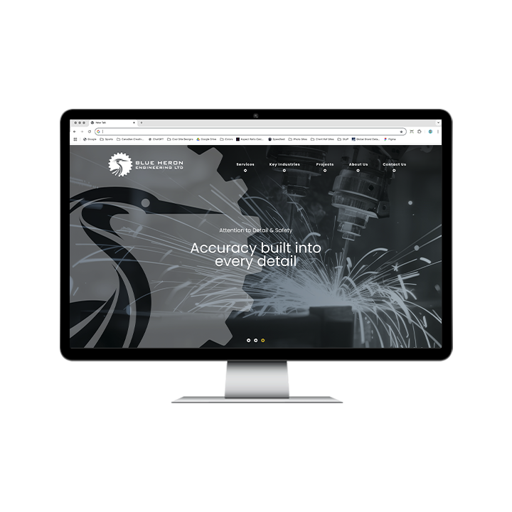 AG Client Page Blue Heron BV3 A desktop computer monitor displaying the Blue Heron Engineering Ltd. website homepage, featuring a large heron logo and a photo of industrial sparks flying from a mechanical tool.