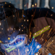 A person wearing a welding helmet works on a project, surrounded by bright flying sparks.
